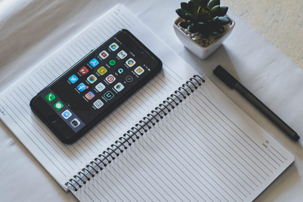 A smart phone, notebook and pen for planning.