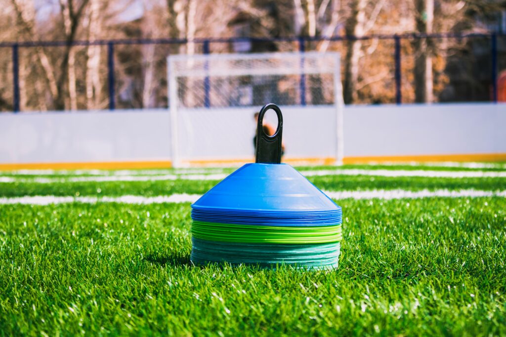 Sports field with goalie cage and collapsible pylon.
