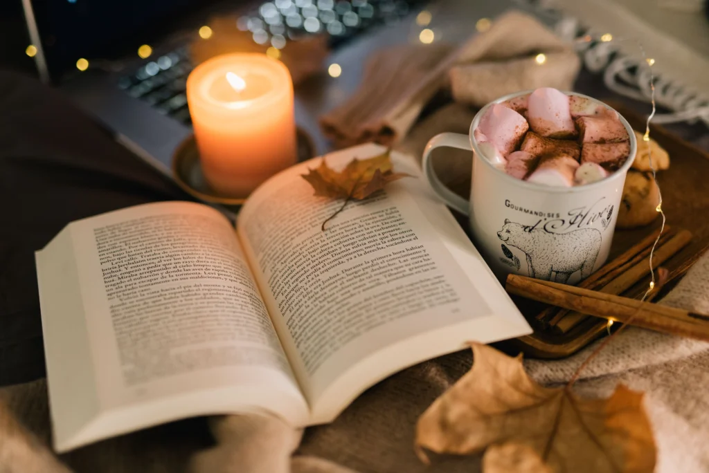 An autumn setting with book, candle and drink. 